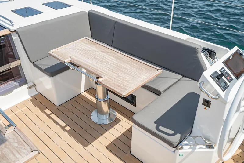 Slide: The Image of 2024 Bavaria C50 yacht cockpit with cushioned seating and wooden table, overlooking the ocean. - 33