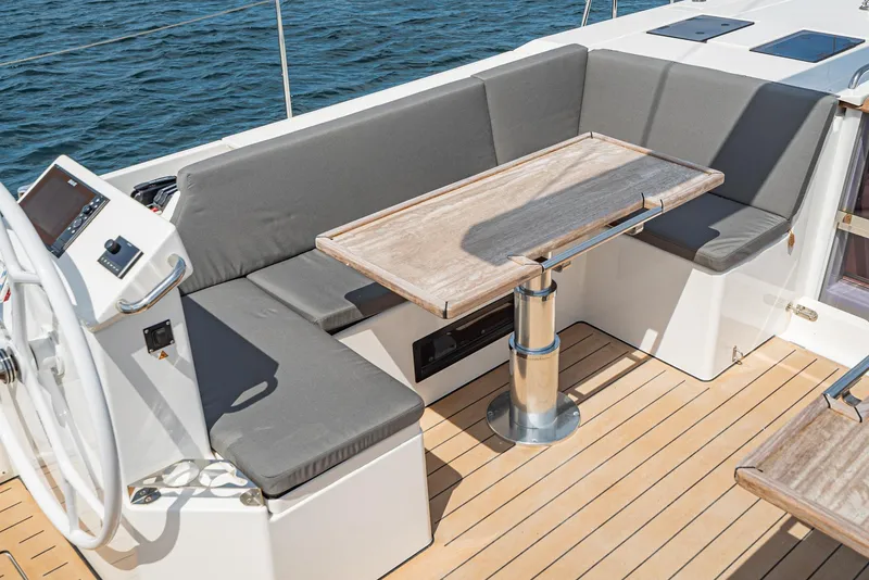 Slide: The Image of 2024 Bavaria C50 yacht cockpit with cushioned seating and wooden table on deck. - 34