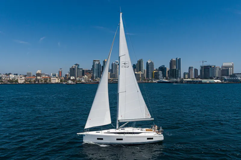 The Image of 2024 Bavaria C42 sailboat cruising near city skyline on a sunny day. - 0