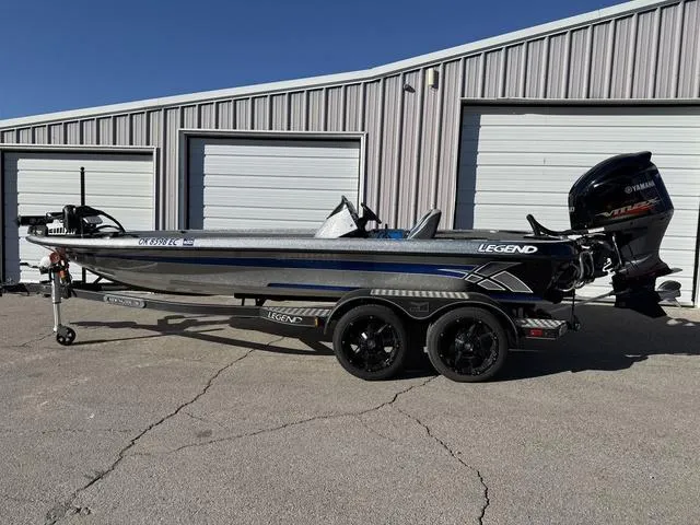 Slide: The Image of 2015 Legend V20 boat with Yamaha engine, parked outside a garage. - 1