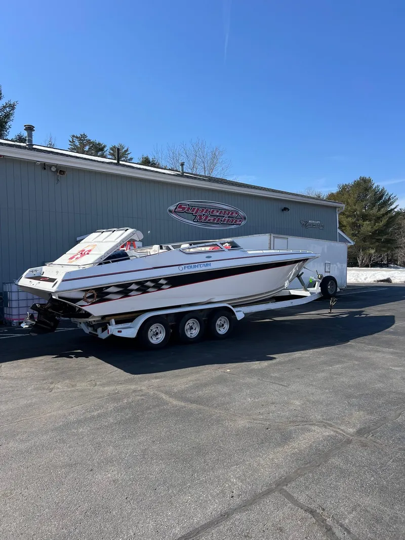 Slide: The Image of 2004 Fountain 29 Fever speedboat on trailer, parked outside a building under clear blue sky. - 10