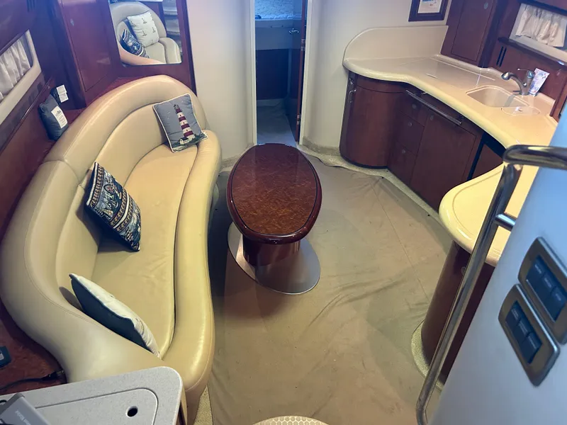 Slide: The Image of 2004 Sea Ray 420 Sundancer interior with beige seating, wooden table, and kitchenette. - 24