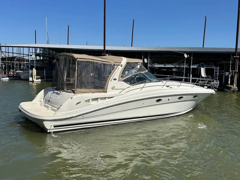 Slide: The Image of 2004 Sea Ray 420 Sundancer yacht docked in marina, featuring sleek design and beige canopy. - 9