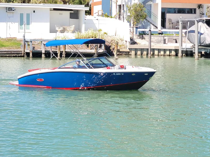 Slide: The Image of 2021 Cobalt CS22 boat with blue canopy on calm water near waterfront homes. - 1