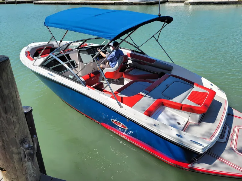 Slide: The Image of 2021 Cobalt CS22 boat with blue canopy and red accents on the water. - 11
