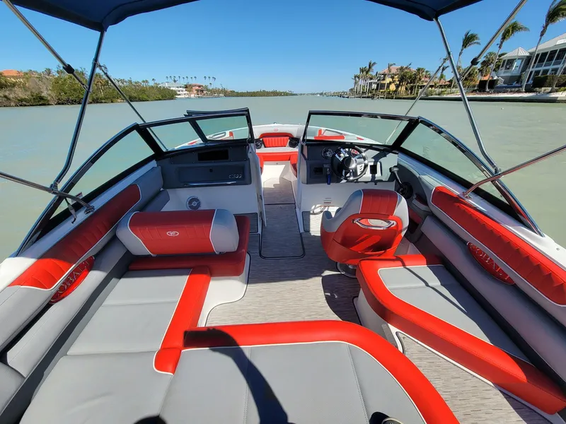 Slide: The Image of 2021 Cobalt CS22 boat interior with red and gray seating on a sunny day. - 2