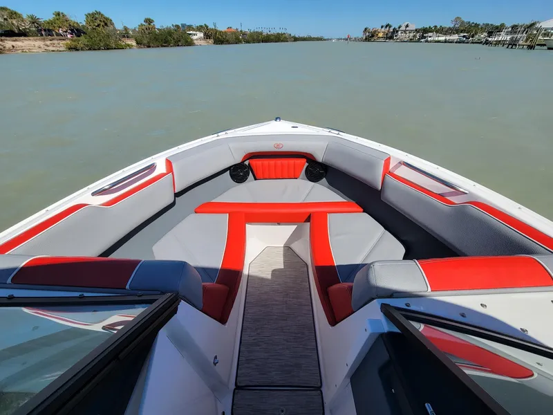 Slide: The Image of 2021 Cobalt CS22 boat interior with red and gray seating on a calm waterway. - 3