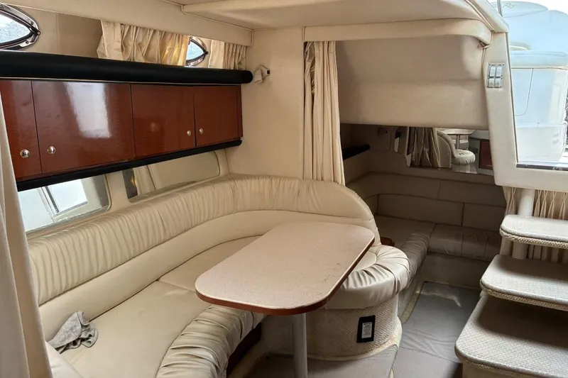 Slide: The Image of Interior of 2002 Sea Ray 340 Sundancer yacht with beige seating and wooden cabinets. - 12