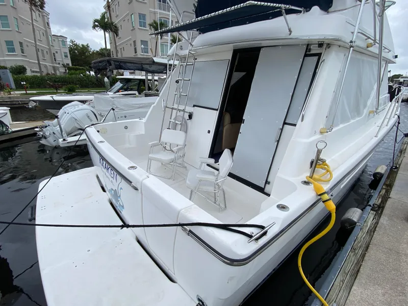 Slide: The Image of 2001 Bayliner 3988 yacht docked, featuring a spacious deck with chairs and ladder. - 4