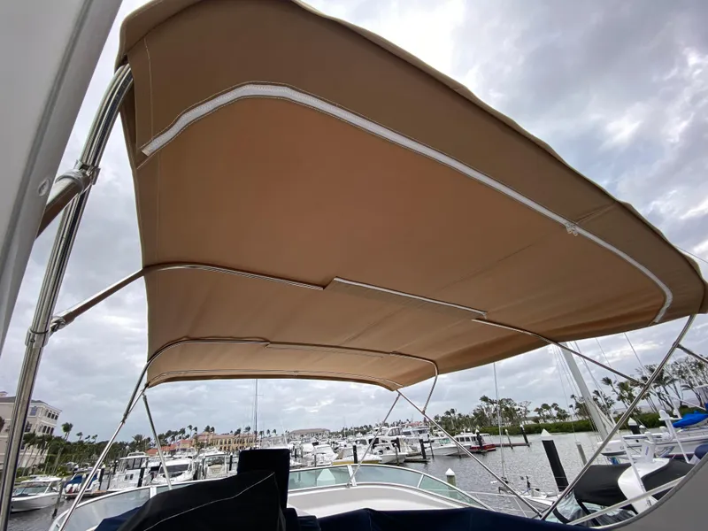 Slide: The Image of 2001 Bayliner 3988 boat with tan canopy, docked at marina under cloudy sky. - 44