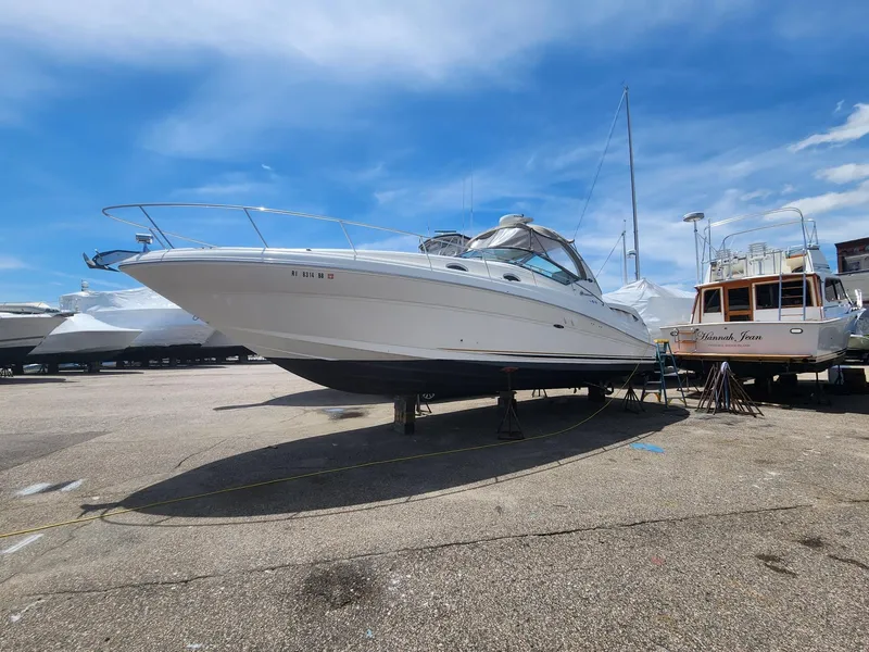 The Image of 2003 Sea Ray 340 Sundancer yacht on dry dock under a clear blue sky. - 1