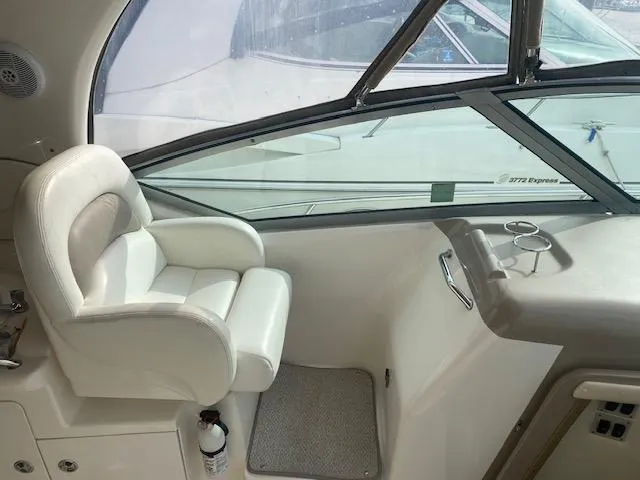 Slide: The Image of 2003 Sea Ray 340 Sundancer helm seat and dashboard, featuring white upholstery and window view. - 14