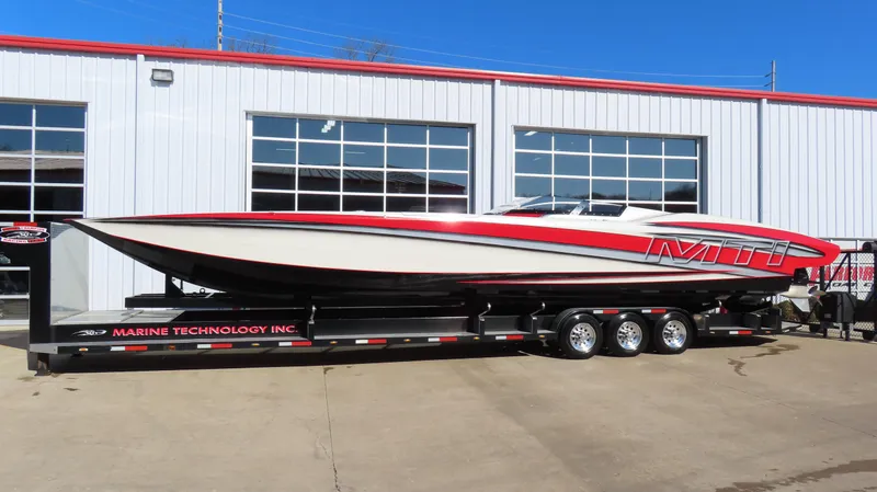 The Image of 2014 MTI 44 powerboat on trailer, red and white design, parked outside a building. - 0