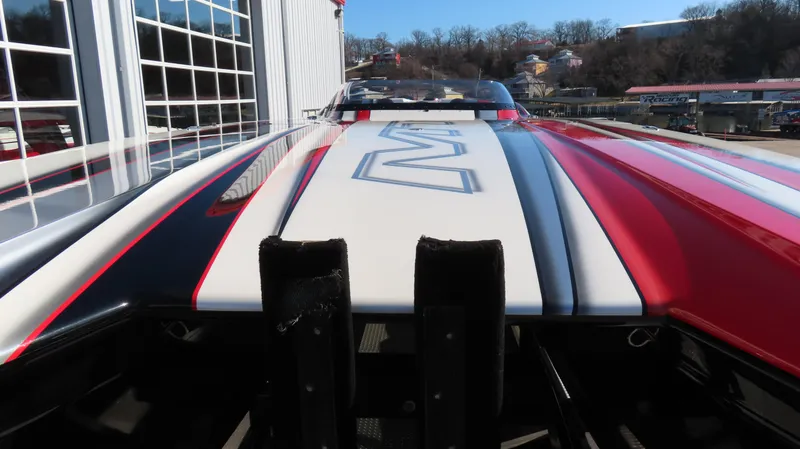 Slide: The Image of 2014 MTI 44 boat with sleek red, black, and white design, docked near a building. - 14