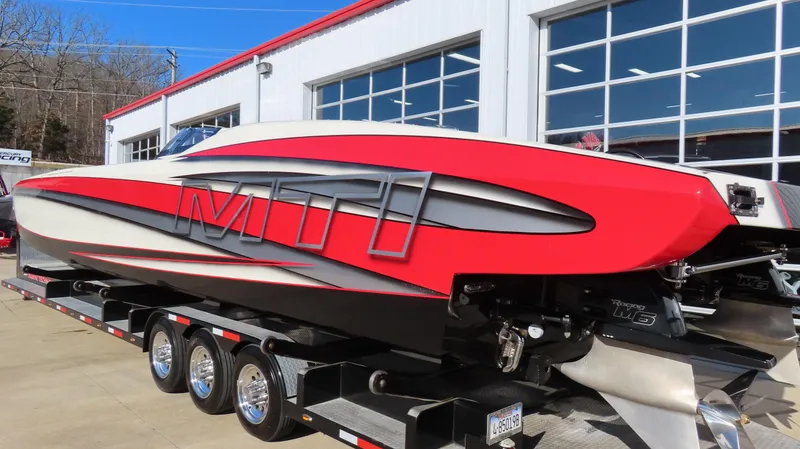 Slide: The Image of 2014 MTI 44 powerboat in red and black on a trailer outside a garage. - 19