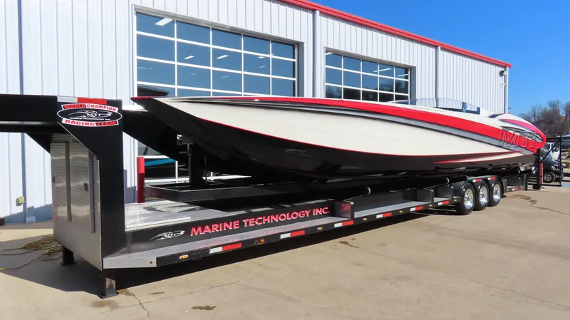 Slide: The Image of 2014 MTI 44 powerboat on trailer outside a garage, featuring red and white design. - 4