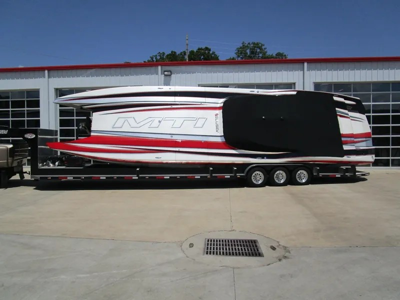 Slide: The Image of 2014 MTI 44 powerboat on trailer, red and white design, parked outside a garage. - 6