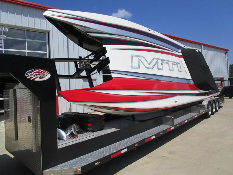 Slide: The Image of 2014 MTI 44 powerboat on trailer, red and white design, parked outside a building. - 8