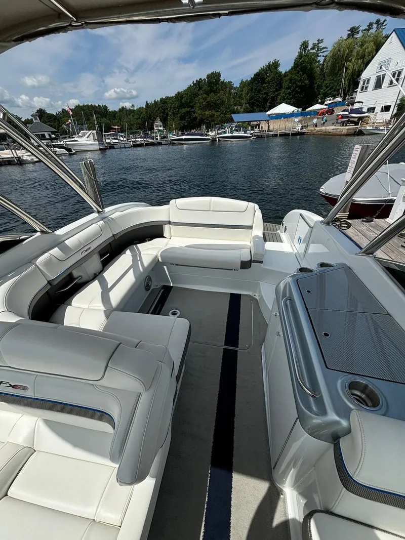 Slide: The Image of 2014 Formula 310 FX5 boat interior with white seating, docked by a scenic waterfront. - 14