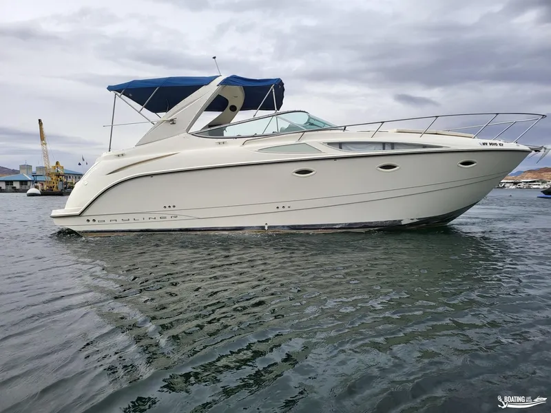 Slide: The Image of 2008 Bayliner 300SB boat with blue canopy on calm water under cloudy sky. - 6