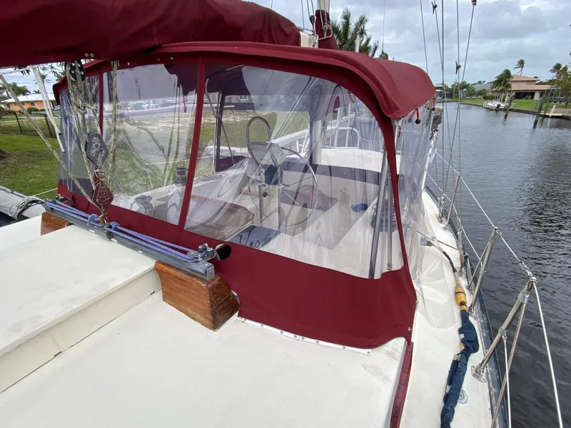 Slide: The Image of 1986 Bruce Roberts 43 Ketch with maroon canopy, docked by a serene waterfront. - 12