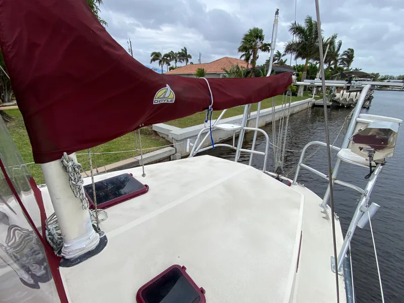 Slide: The Image of 1986 Bruce Roberts 43 Ketch sailboat deck with maroon accents, docked near lush greenery. - 14