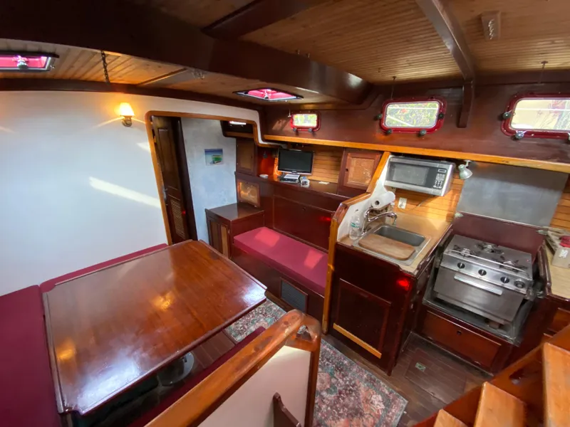 Slide: The Image of 1986 Bruce Roberts 43 Ketch docked by a scenic waterfront with red sail cover. - 25