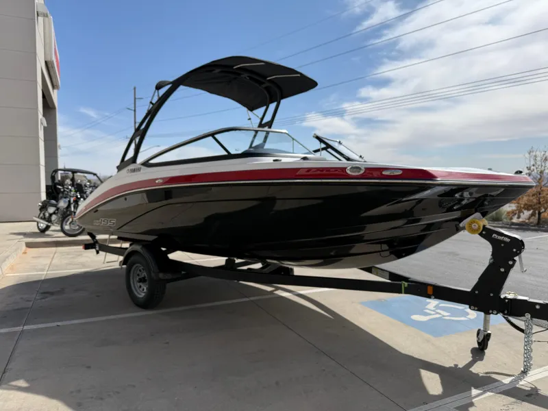 Slide: The Image of 2025 Yamaha Boats AR195 on trailer, sleek black and red design, parked outdoors. - 10