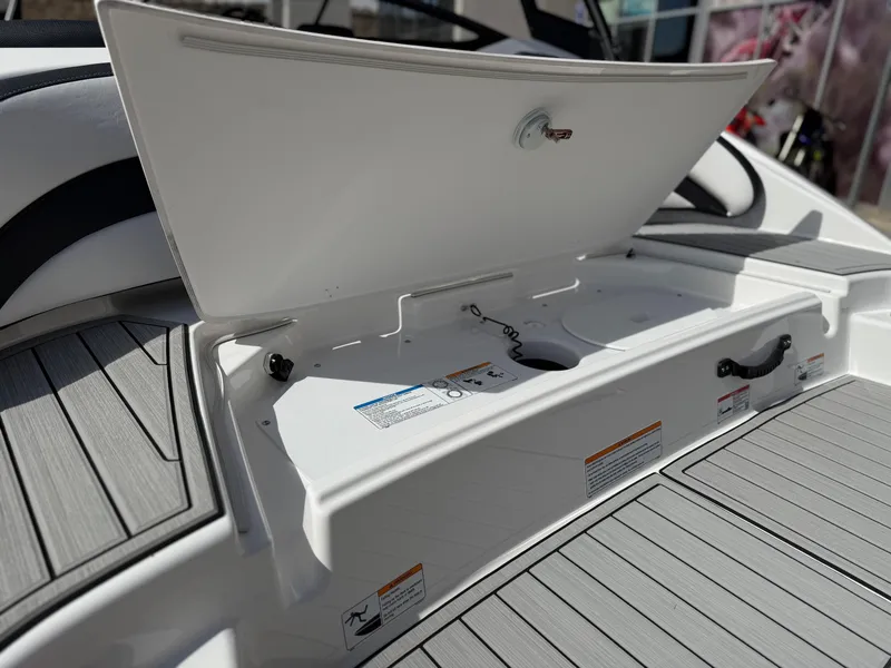 Slide: The Image of 2025 Yamaha Boats AR195 storage compartment with open lid, showcasing interior details. - 19
