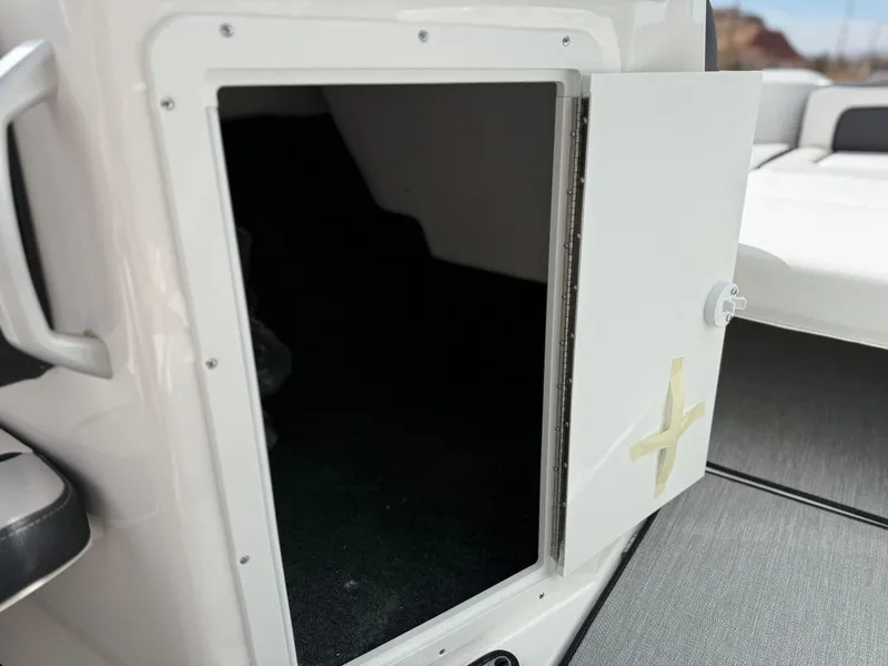 Slide: The Image of 2025 Yamaha Boats AR195 storage compartment with open door, showcasing interior space. - 43