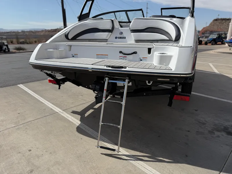 Slide: The Image of 2025 Yamaha Boats AR195 with swim platform and ladder, parked on concrete surface. - 6
