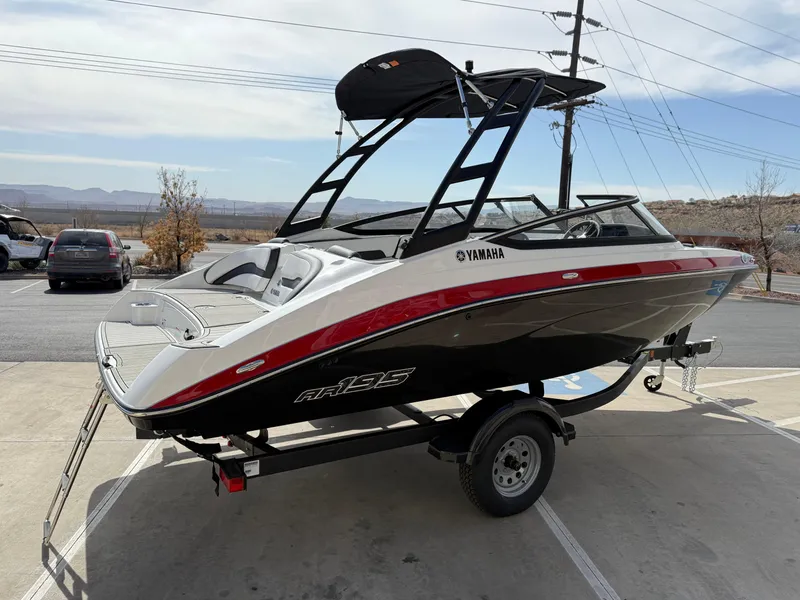 Slide: The Image of 2025 Yamaha AR195 boat on trailer, black and white with red accents, parked outdoors. - 8