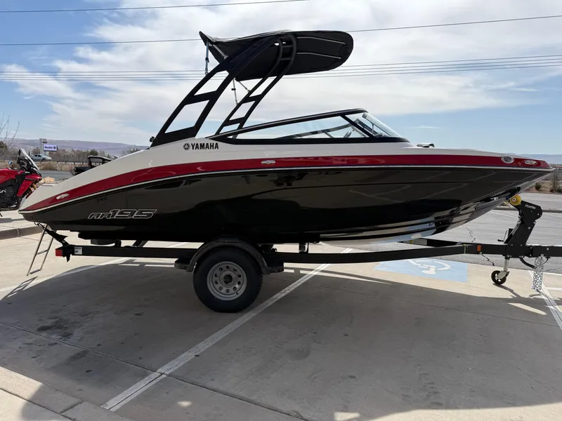 Slide: The Image of 2025 Yamaha Boats AR195 on trailer, sleek black and red design, parked outdoors. - 9