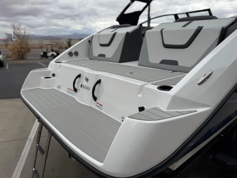 Slide: The Image of 2025 Yamaha Boats AR220, sleek design, rear view, gray and white color scheme, outdoor setting. - 21