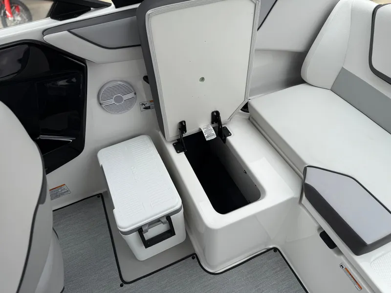 Slide: The Image of 2025 Yamaha Boats AR220 interior storage compartment with open lid and seating area. - 34