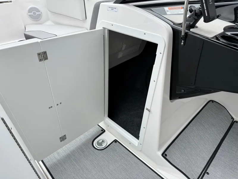 Slide: The Image of 2025 Yamaha Boats AR220 interior storage compartment with open door, showcasing sleek design. - 47