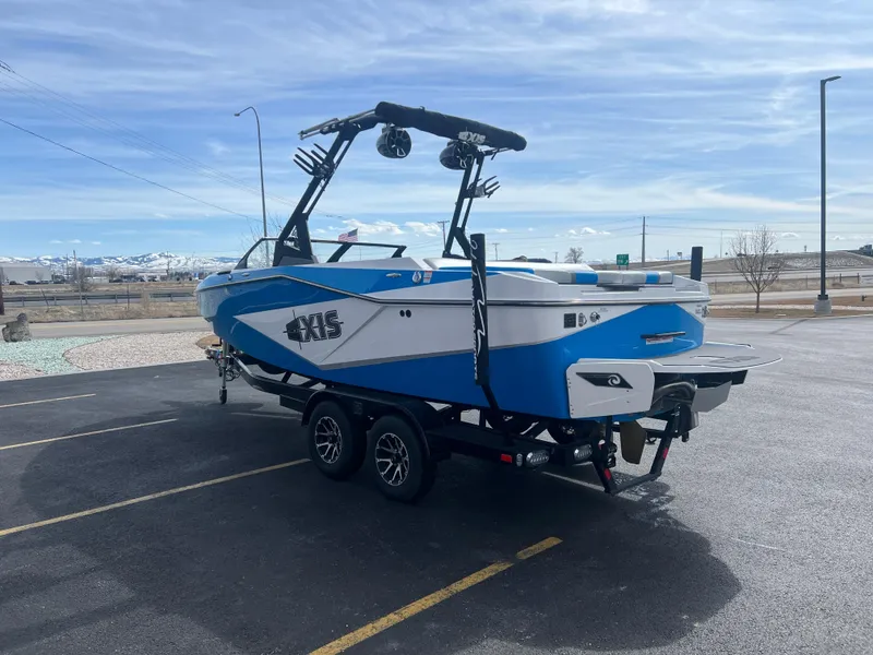 Slide: The Image of 2023 Axis Wake Research T220 boat on trailer, blue and white design, parked outdoors. - 7