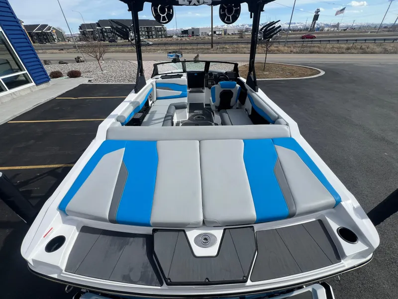 Slide: The Image of 2023 Axis Wake Research T220 boat with blue and gray seating, parked outdoors. - 9