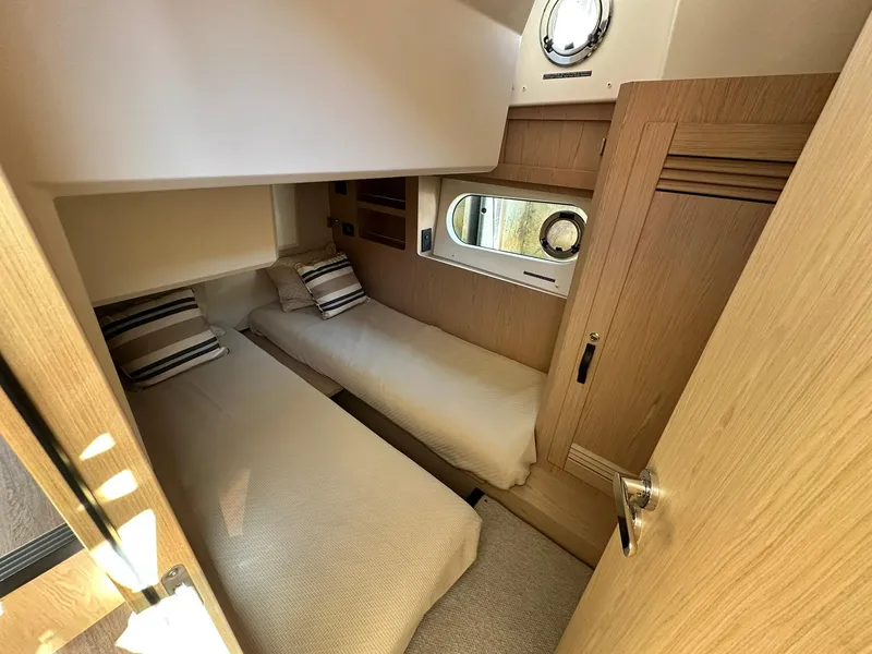 Slide: The Image of 2023 Beneteau Swift Trawler 48 cabin with twin beds and modern wood finish. - 18