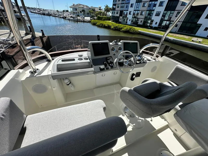 Slide: The Image of 2023 Beneteau Swift Trawler 48 helm with modern controls, docked at marina. - 25