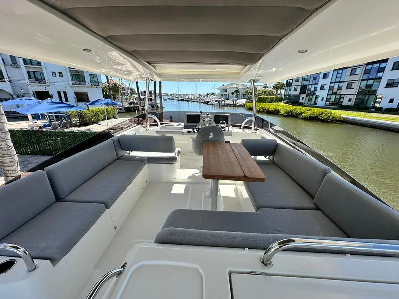 Slide: The Image of 2023 Beneteau Swift Trawler 48, spacious deck with seating, docked near waterfront buildings. - 27