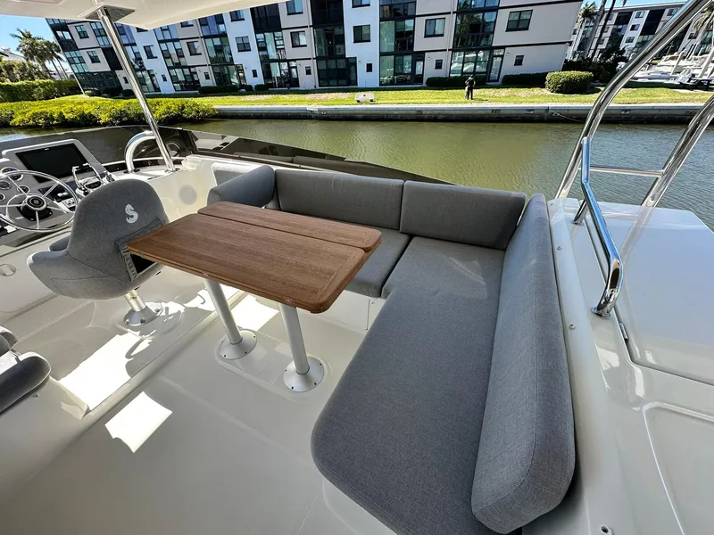 Slide: The Image of 2023 Beneteau Swift Trawler 48, outdoor seating area with table, near waterfront buildings. - 29