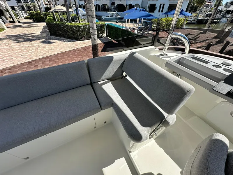 Slide: The Image of 2023 Beneteau Swift Trawler 48 seating area with gray cushions, dockside view. - 30
