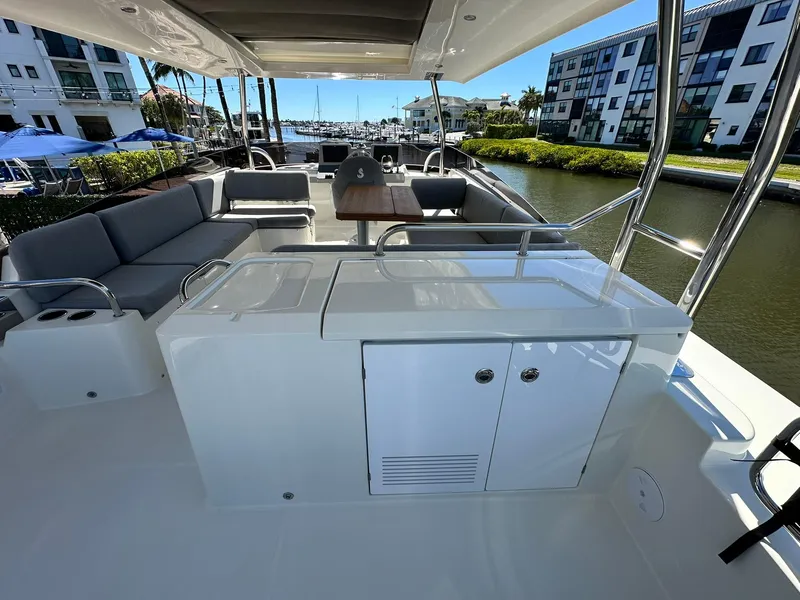Slide: The Image of 2023 Beneteau Swift Trawler 48, spacious deck with seating and table, docked at marina. - 32