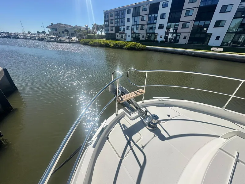 Slide: The Image of 2023 Beneteau Swift Trawler 48 bow view near waterfront buildings. - 39