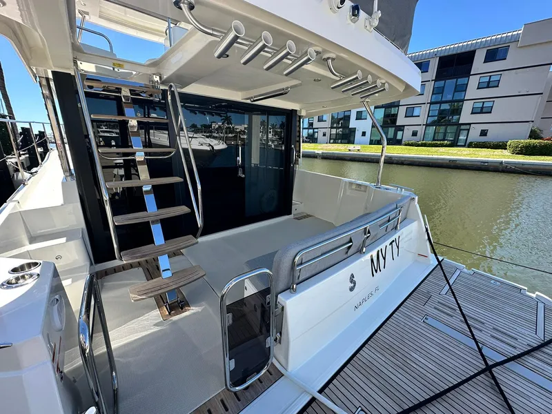 Slide: The Image of 2023 Beneteau Swift Trawler 48, rear deck view, docked by modern buildings. - 4