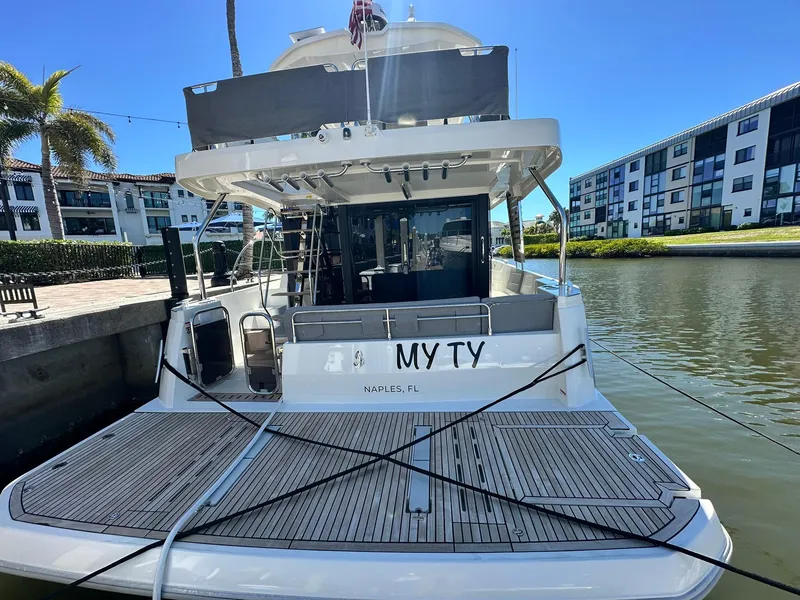 Slide: The Image of 2023 Beneteau Swift Trawler 48 docked, rear view, sunny day, waterfront setting. - 5