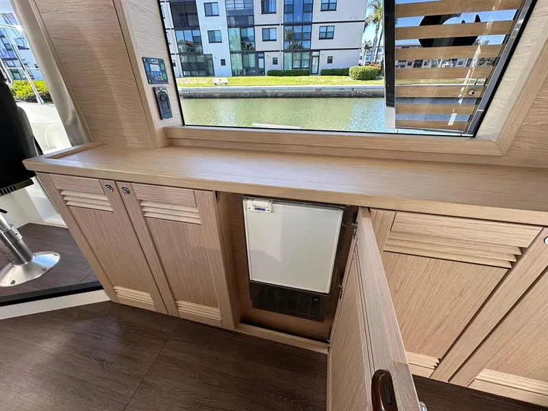 Slide: The Image of 2023 Beneteau Swift Trawler 48 interior with wooden cabinetry and window view. - 8