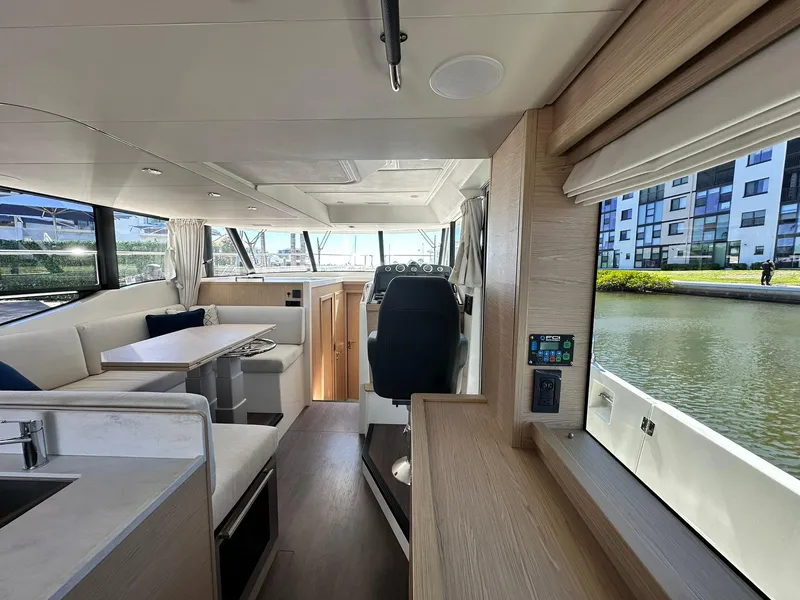 Slide: The Image of 2023 Beneteau Swift Trawler 48 interior with modern seating and helm, near waterfront. - 9