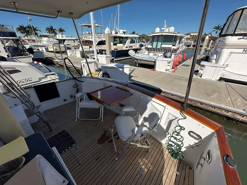 Slide: The Image of 2000 Legacy Yachts 40 Sedan at marina, featuring spacious deck with chairs and table. - 10